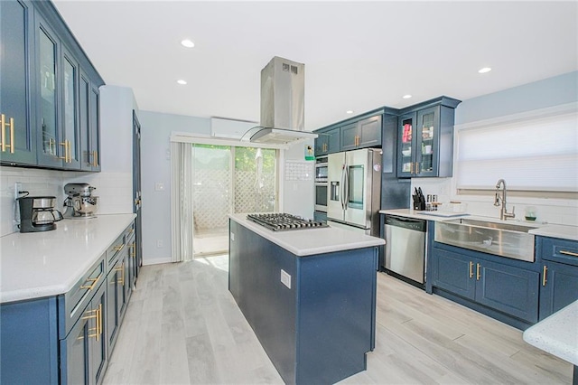 kitchen with appliances with stainless steel finishes, a sink, light wood-style floors, island exhaust hood, and a kitchen island