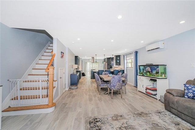 dining space featuring stairway, baseboards, a wall unit AC, and light wood-style flooring