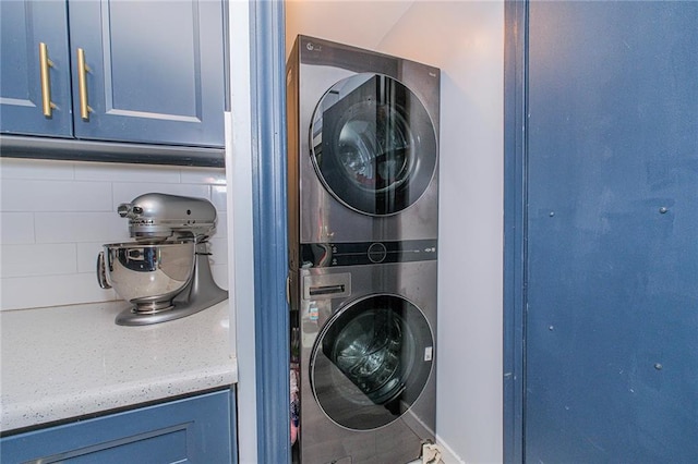 clothes washing area with stacked washer and clothes dryer and laundry area