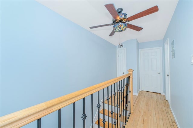 hall with baseboards, visible vents, an upstairs landing, and light wood-style floors