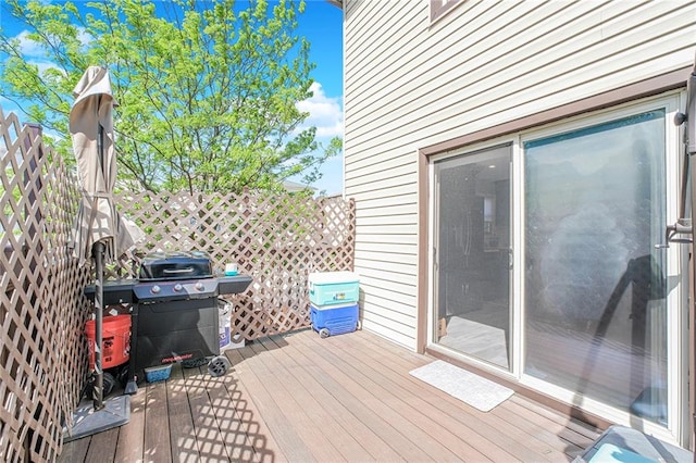 wooden terrace featuring fence and a grill