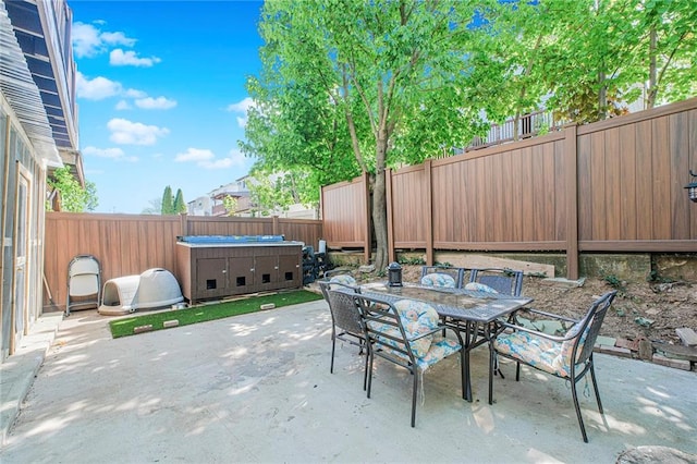 view of patio with outdoor dining area, a fenced backyard, and a hot tub