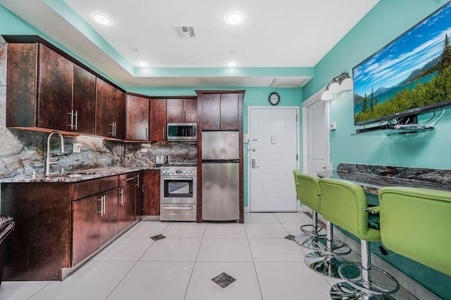 2113 Kings Hwy Unit 2B, Brooklyn, NY 11229 - kitchen featuring appliances with stainless steel finishes, a sink, backsplash, dark brown cabinetry, and dark stone counters