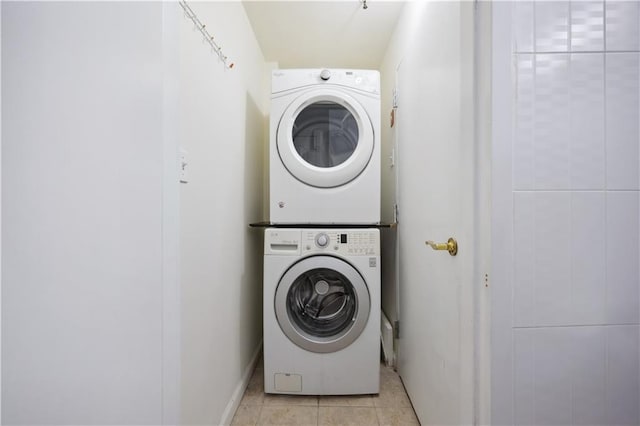 washroom featuring stacked washing maching and dryer, light tile patterned floors, and laundry area