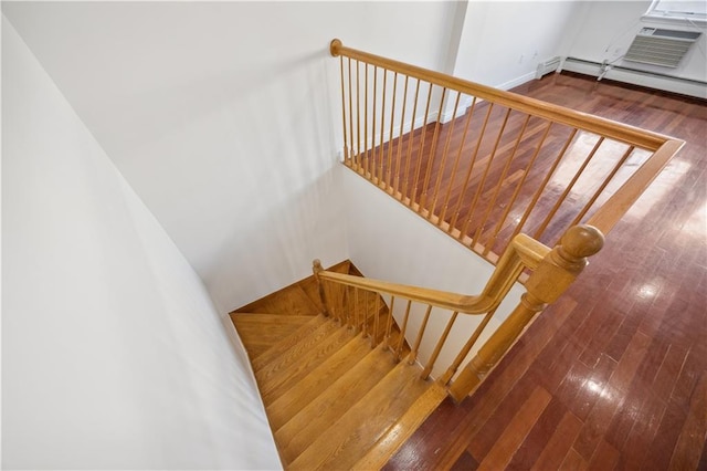 staircase with wood-type flooring and a baseboard heating unit