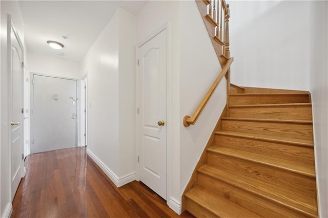 staircase featuring baseboards and wood finished floors