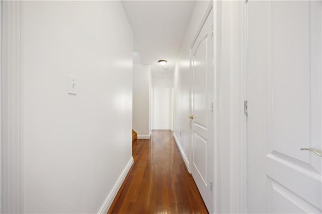 hallway with baseboards and dark wood-style floors