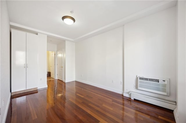 interior space with baseboards, a baseboard radiator, an AC wall unit, and wood finished floors
