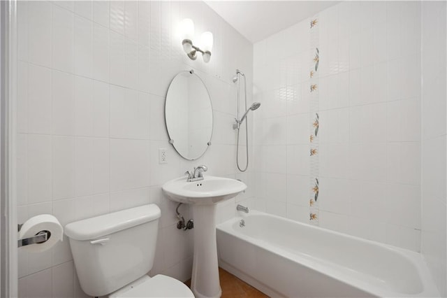 full bathroom with a sink, washtub / shower combination, toilet, and tile walls