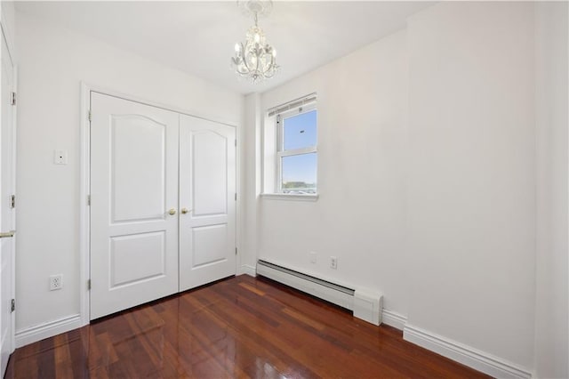 unfurnished bedroom featuring an inviting chandelier, a closet, baseboards, baseboard heating, and dark wood-style floors