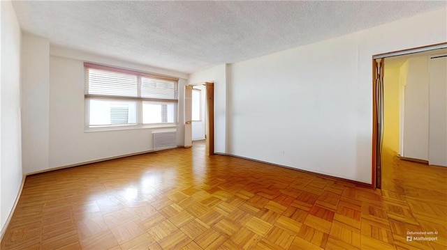unfurnished room with a textured ceiling, visible vents, and baseboards