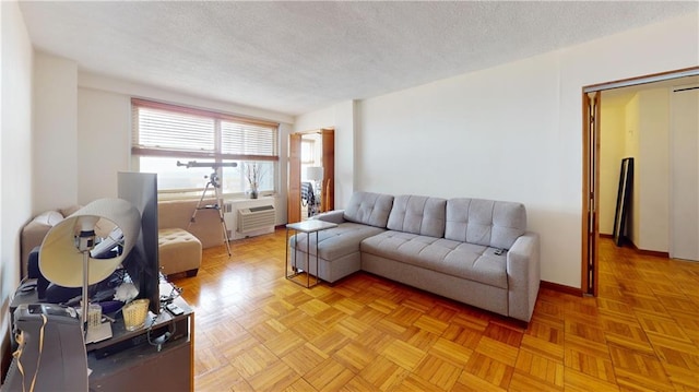 living room featuring baseboards, a textured ceiling, and a wall mounted AC