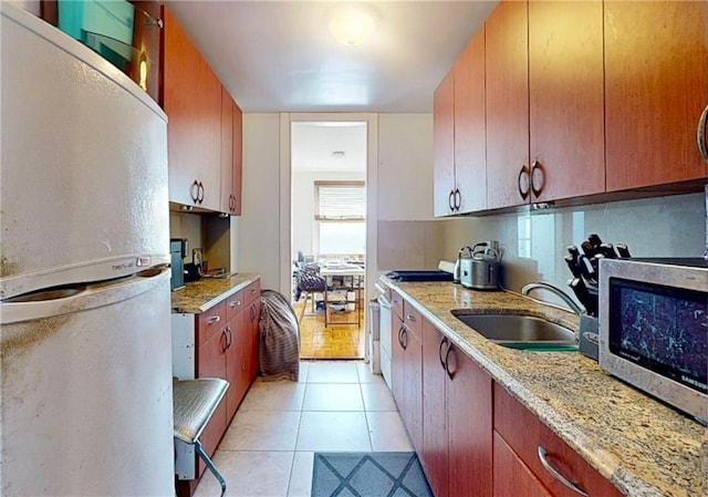 kitchen with range with gas stovetop, freestanding refrigerator, light tile patterned flooring, stainless steel microwave, and a sink