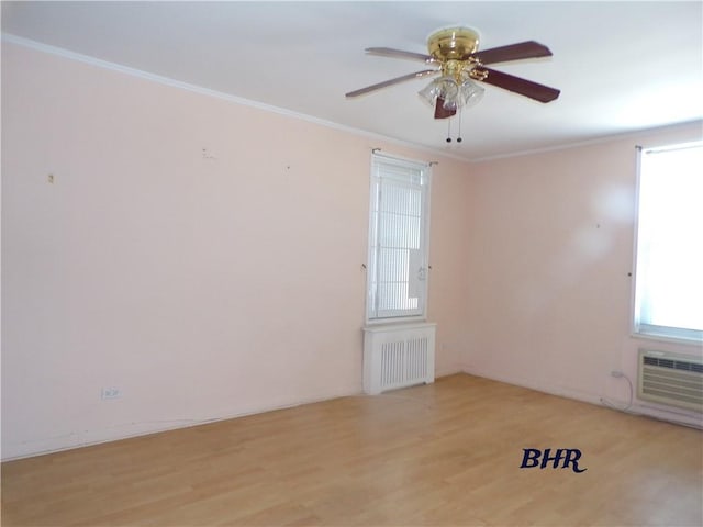 spare room featuring ornamental molding, light wood finished floors, a ceiling fan, and radiator heating unit
