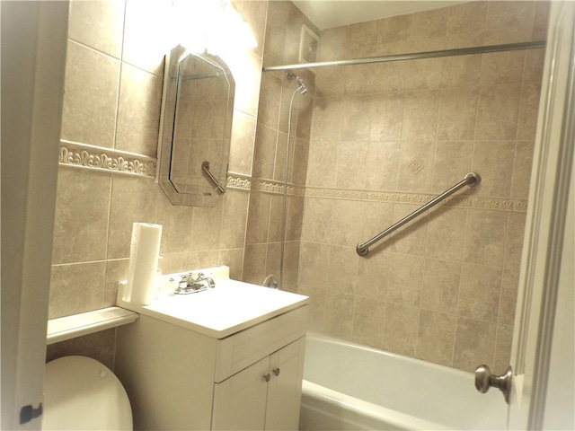 bathroom with shower / bath combination, vanity, toilet, and tile walls