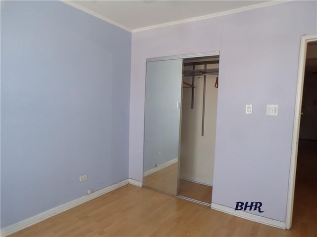 unfurnished bedroom featuring baseboards, ornamental molding, a closet, and light wood-style flooring