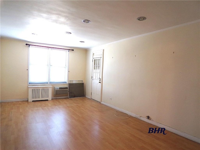 unfurnished room featuring crown molding, baseboards, light wood-style flooring, and radiator