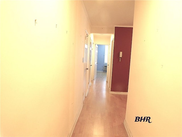 hall featuring crown molding, baseboards, and light wood finished floors