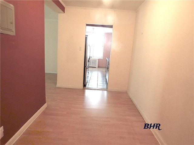 hallway with crown molding, baseboards, radiator heating unit, and wood finished floors