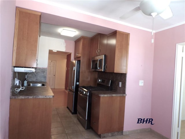 kitchen with ceiling fan, brown cabinetry, backsplash, appliances with stainless steel finishes, and a sink