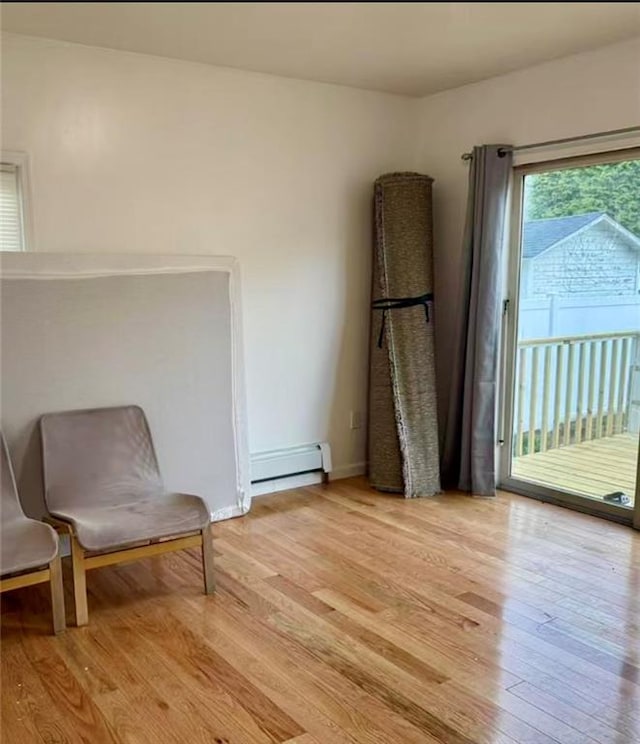 living area with baseboards, light wood-style flooring, and a baseboard heating unit