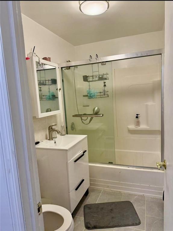 bathroom with vanity, combined bath / shower with glass door, tile patterned flooring, and toilet