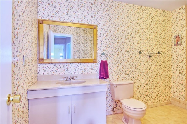 bathroom with toilet, wallpapered walls, tile patterned flooring, and vanity