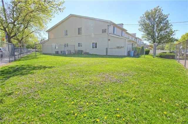 rear view of house with fence and a yard