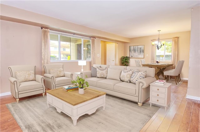 living room with baseboards, an inviting chandelier, and light wood-style flooring