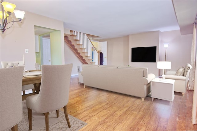 living room with stairs, an inviting chandelier, and light wood finished floors