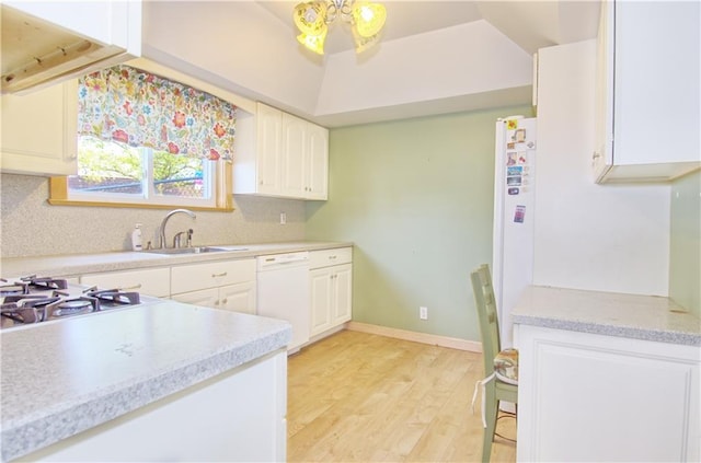 kitchen featuring decorative backsplash, dishwasher, a sink, light countertops, and light wood finished floors