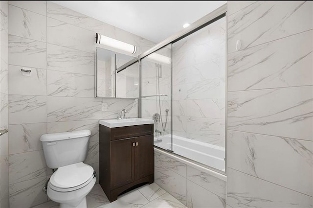 full bath featuring vanity, toilet, marble finish floor, tiled shower / bath, and tile walls