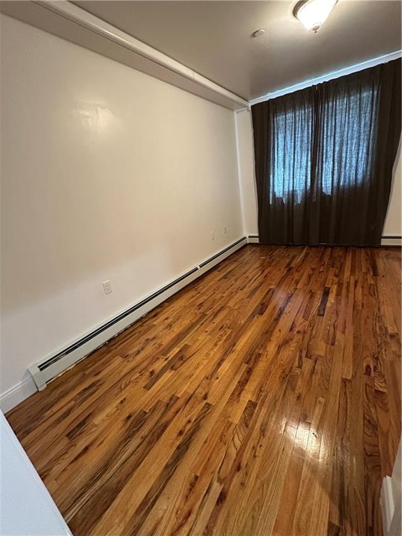 spare room with baseboard heating and hardwood / wood-style floors