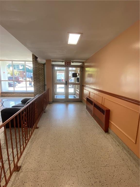 hall with french doors, wainscoting, and a decorative wall
