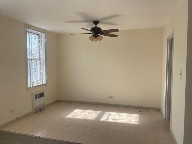 unfurnished room with baseboards, a ceiling fan, radiator, and light tile patterned floors