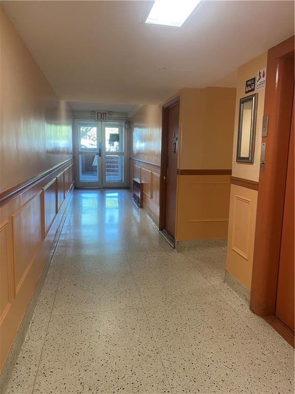 hallway featuring wainscoting, french doors, and a decorative wall