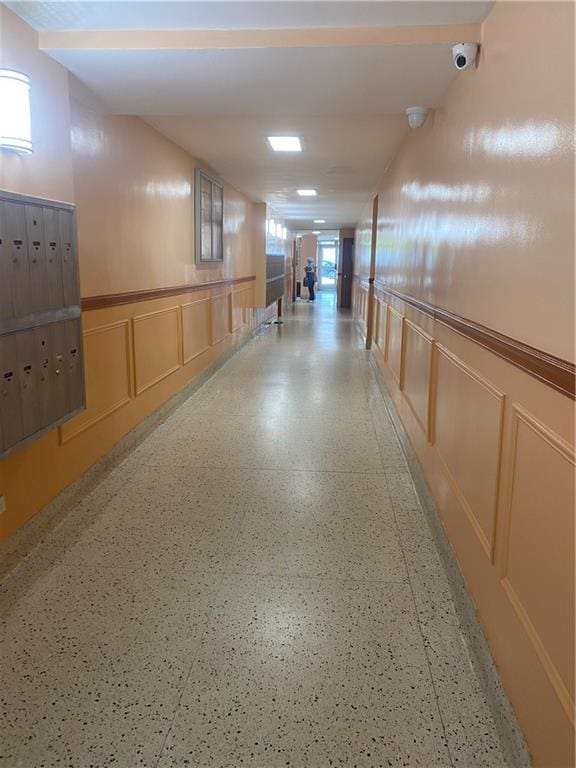 hall featuring a wainscoted wall, a decorative wall, and mail area