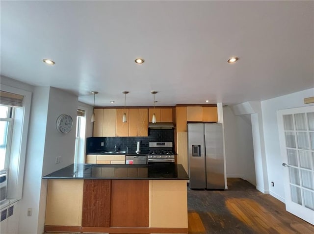 kitchen featuring a peninsula, dark countertops, under cabinet range hood, tasteful backsplash, and stainless steel appliances