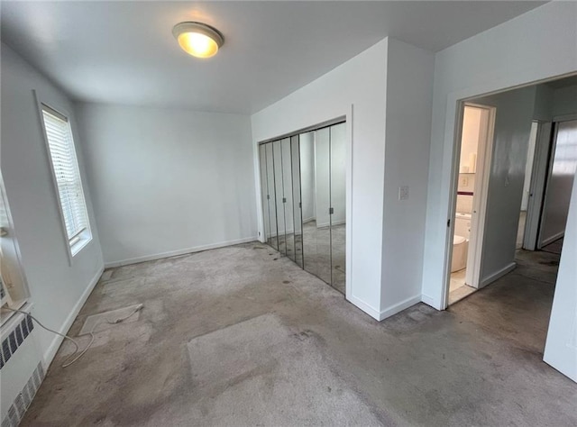 unfurnished bedroom featuring radiator, baseboards, carpet, and a closet