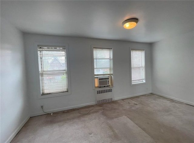 empty room with baseboards, carpet, radiator heating unit, and cooling unit
