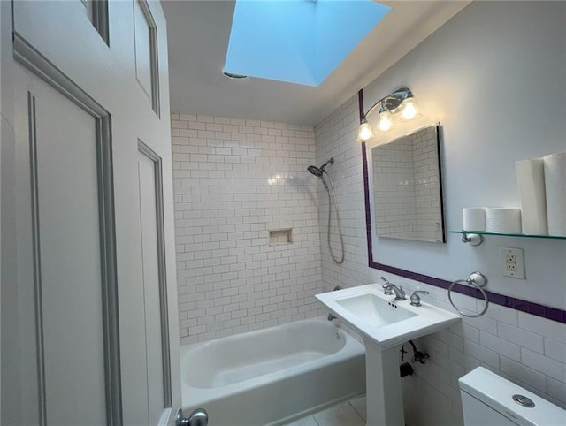 bathroom featuring shower / tub combination, a skylight, toilet, and tile walls
