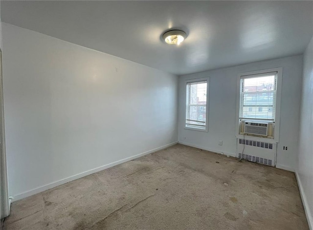empty room with carpet flooring, baseboards, radiator, and cooling unit