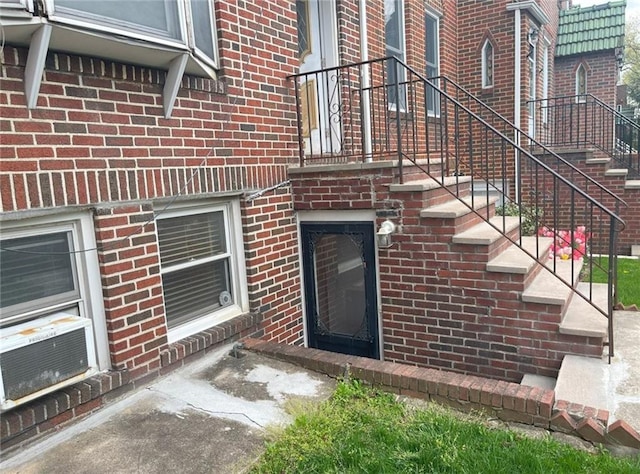 view of exterior entry with cooling unit and brick siding
