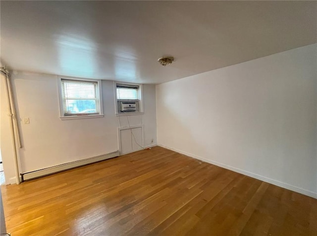 spare room with baseboards, cooling unit, a baseboard heating unit, and wood finished floors