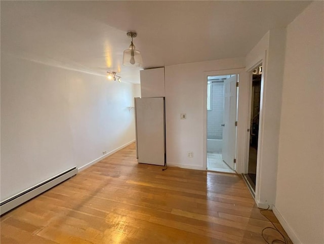 unfurnished room with baseboards, baseboard heating, and light wood-style floors
