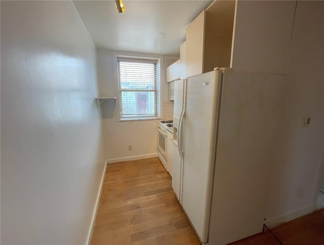 kitchen featuring baseboards, light wood finished floors, white appliances, and white cabinetry