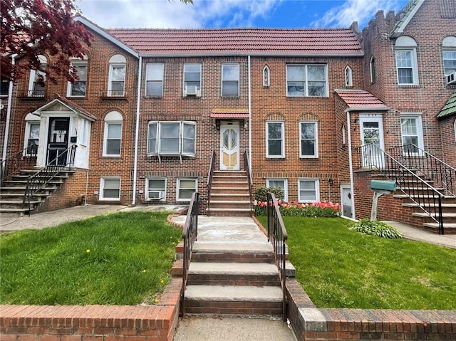 view of front facade featuring a tiled roof, stairs, and a front lawn