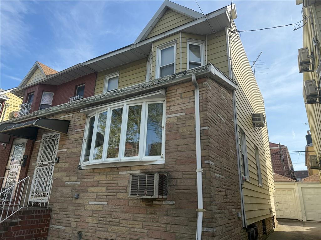 1032 68th St, Brooklyn, NY 11219 - view of property exterior featuring an AC wall unit, a garage, and stone siding