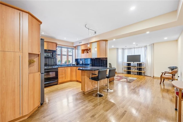 3821 Avenue S, Brooklyn, NY 11234 - kitchen with a peninsula, a kitchen bar, light brown cabinetry, dark countertops, and black appliances