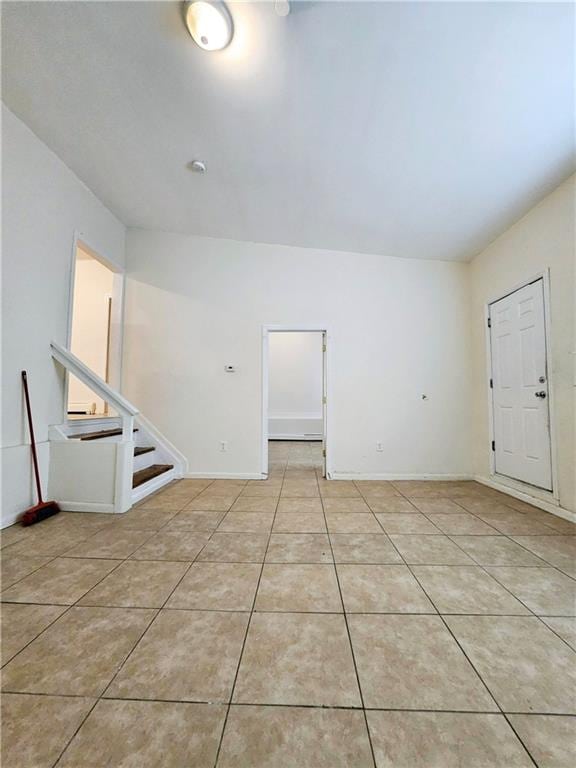 unfurnished room featuring baseboards, stairs, and light tile patterned flooring